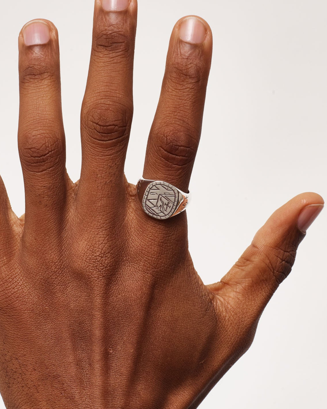 Hand wearing a ring on a plain background