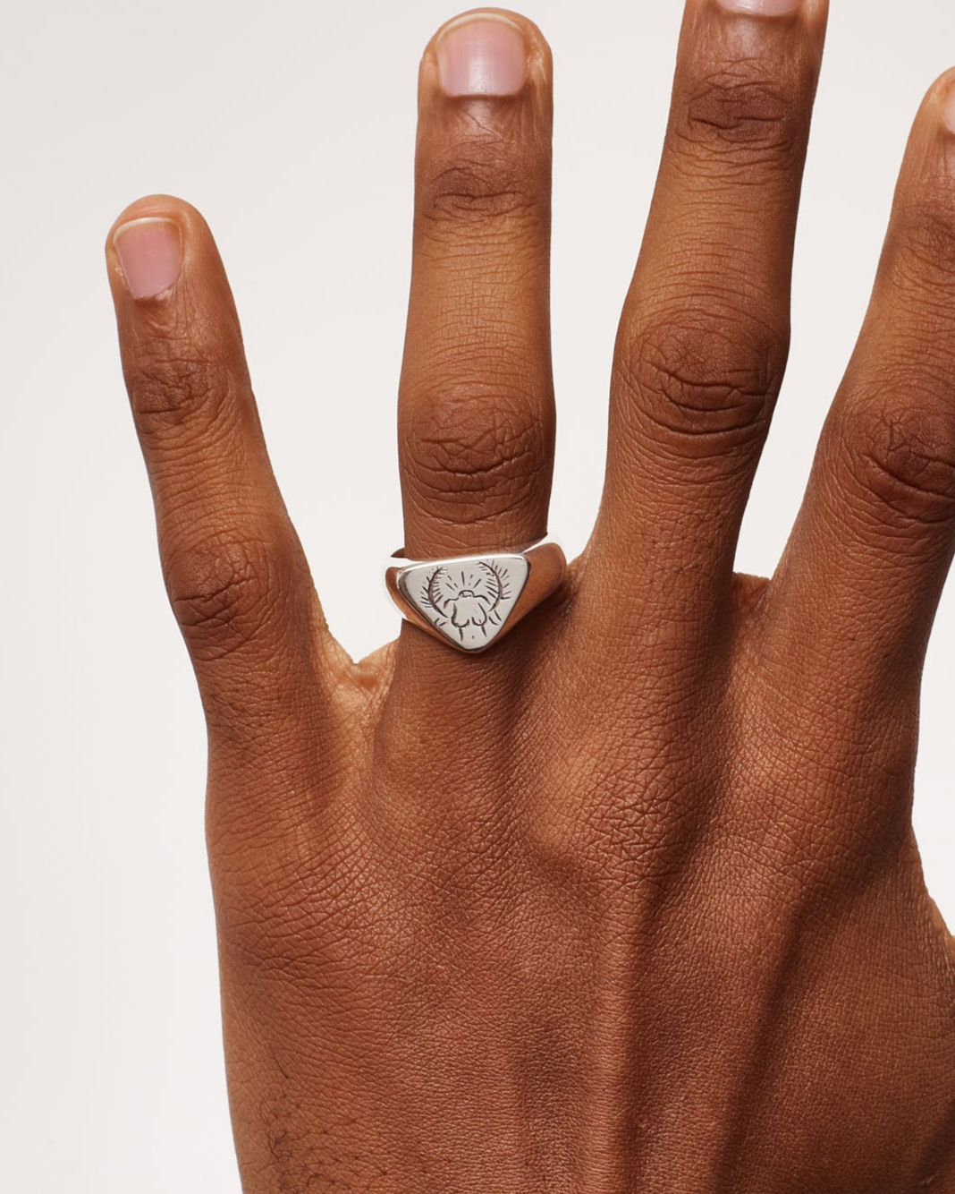 Hand wearing a ring on a plain background