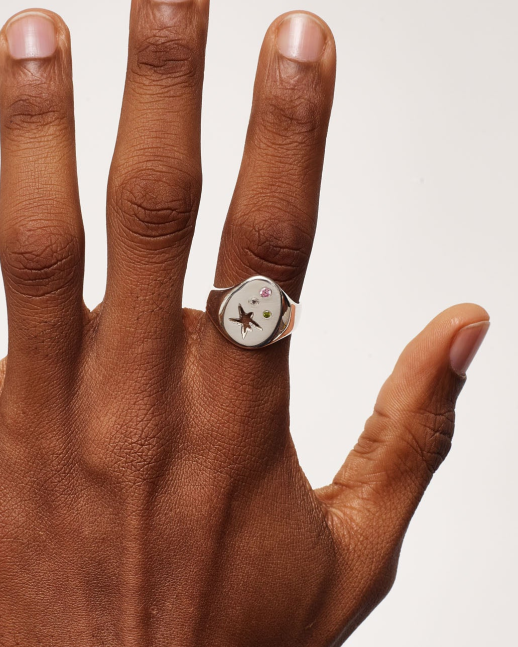 Hand wearing a ring on a plain background