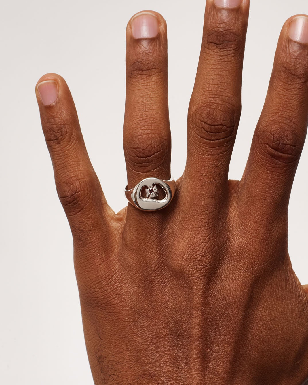 Hand wearing a ring on a plain background
