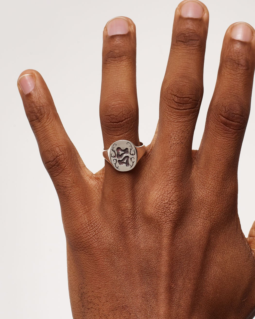 Hand wearing a diamond ring on a plain background