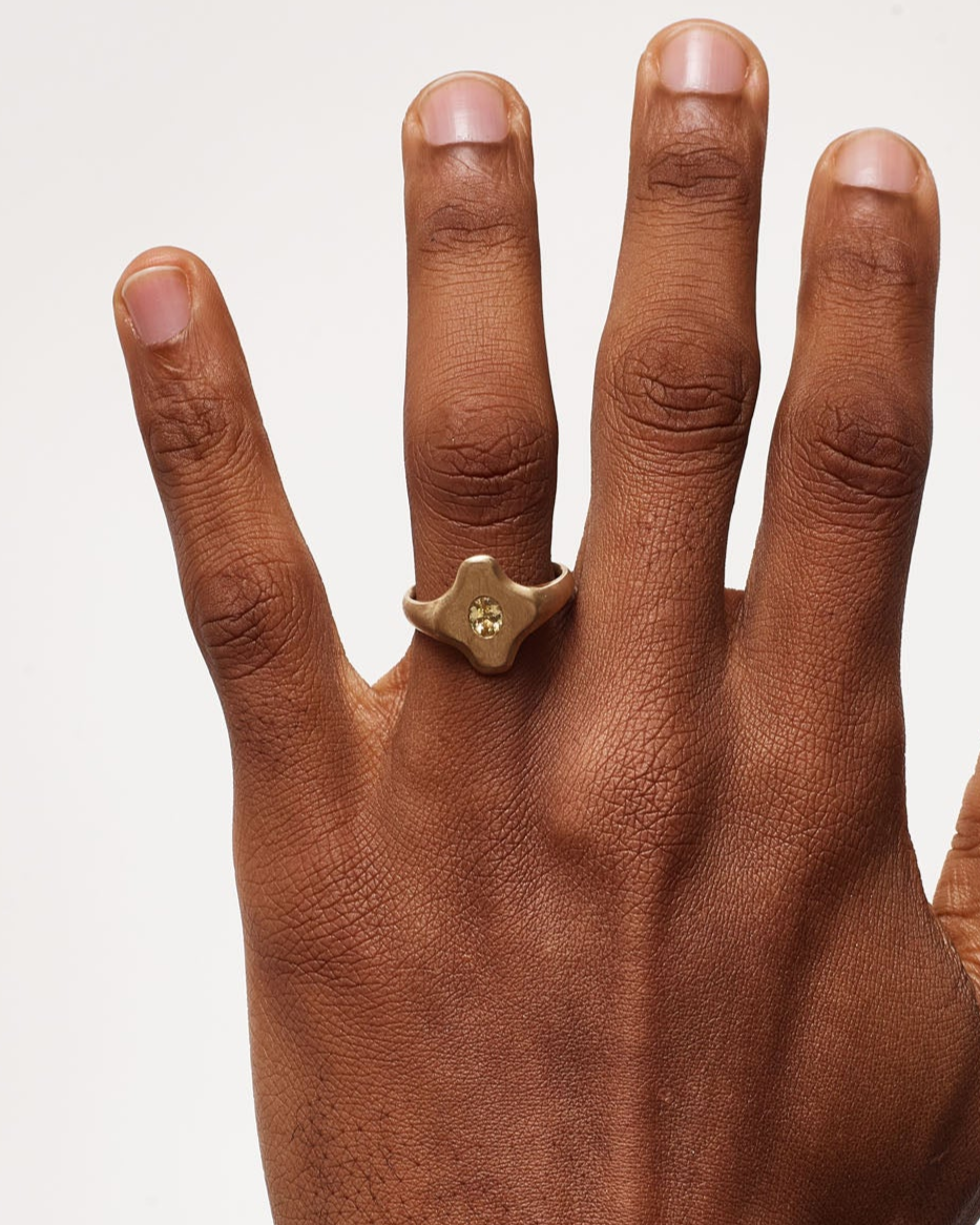 Hand wearing a gold ring on a plain background