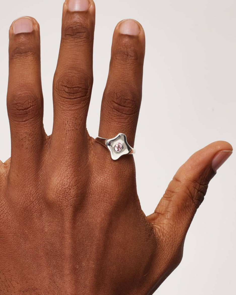Hand wearing a silver ring on a plain background