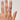 Hand wearing a silver ring with a clover design on a plain background
