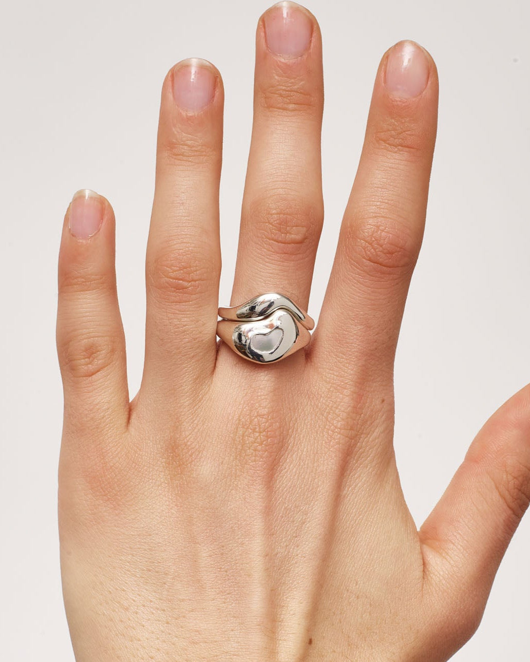 Hand wearing a ring on a plain background