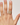 Hand wearing a gold ring with a gemstone on a plain background